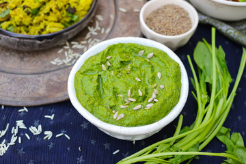 Green spinach dip sauce paste spread in bowl with sunflower seeds, oil and cumin. Organic healthy food snack or appetizer 