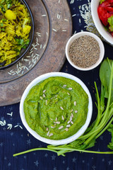 Green spinach dip sauce paste spread in bowl with sunflower seeds, oil and cumin. Organic healthy food snack or appetizer 