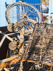 Rusty metal junk objects (bicycle, shopping cart) collected from the sea at an industrial quay / cargo port area.