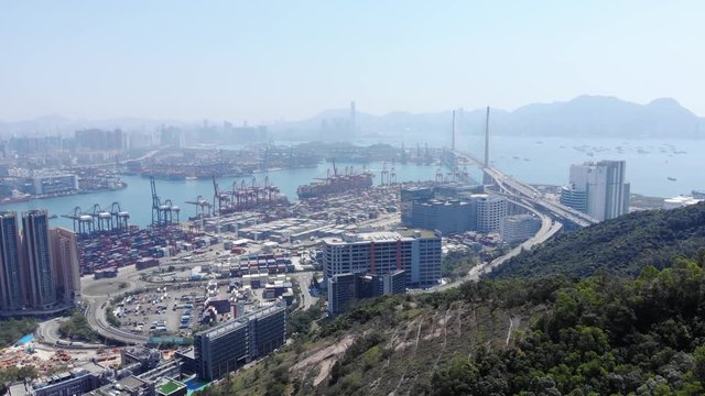 Large industrial area on shore at mountain foot, container terminals if Hong Kong international port. Cargo shipping facility at Tsing Yi island, aerial panoramic shot, camera fly forward