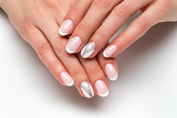 Wedding manicure. White French manicure with silver painting on short oval nails on a white background.