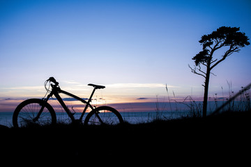 Naklejka na ściany i meble beautiful sunset on the sea and the silhouette of a bicycle