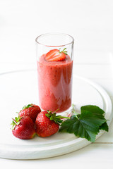Strawberry and banana smoothie glass on white wooden background. Detox and healthy eating concept