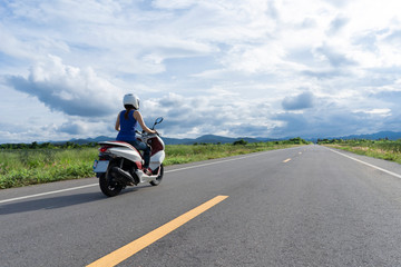 Girl rides motorbike straight to the horisont sunny day clouds sky