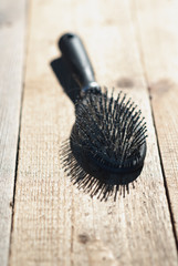 Black comb with blonde hair lies on floorboards.