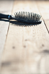 Black comb with blonde hair lies on floorboards.