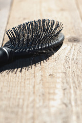 Black comb with blonde hair lies on floorboards.