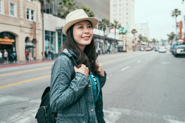 Happy young asian woman smiling with teeth smile outdoors walking on city street cross zebra at sun...