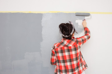 Single woman painting a wall in her apartment. DIY home renovation.