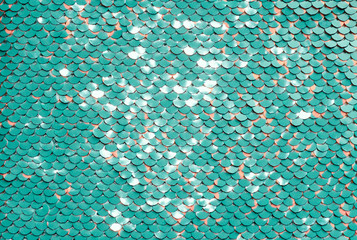 Fototapeta na wymiar Sequin fabric background. Close-up shot of glittery blue or aquamarine colored sequins texture with coral dots