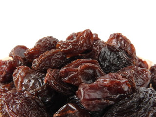From view and close up of a pile of raisins isolated on white background. A raisin is a dried grape. Dry food. Texture detail of raisin surface. Food concept. With copy space.