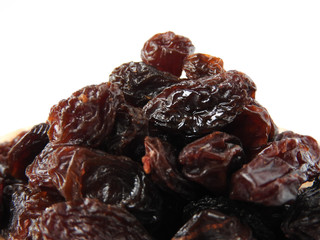 From view and close up of a pile of raisins isolated on white background. A raisin is a dried grape. Dry food. Texture detail of raisin surface. Food concept. With copy space.