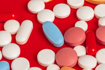 Many medicine pills close up on red background