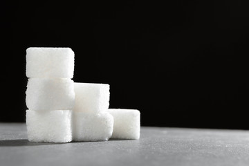 Sugar lumps piled up together against a black background