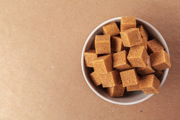 Brown cane sugar cubes on a light brown background