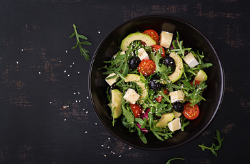 Green salad with sliced avocado, cherry tomatoes, black olives and cheese. Healthy diet vegetarian summer vegetable salad. Table setting. Food concept. Top view.