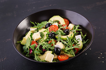 Green salad with sliced avocado, cherry tomatoes, black olives and cheese. Healthy diet vegetarian summer vegetable salad. Table setting. Food concept.