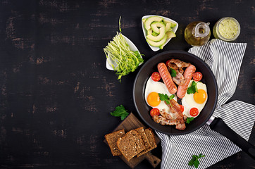 English breakfast - fried egg, tomatoes, sausage and bacon. Top view