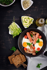 English breakfast - fried egg, tomatoes, sausage and bacon. Top view