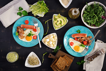 English breakfast - fried egg, tomatoes, sausage and bacon. Top view