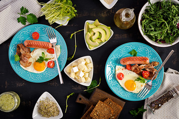 English breakfast - fried egg, tomatoes, sausage and bacon. Top view