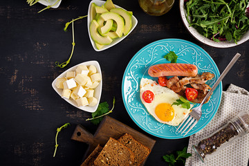 English breakfast - fried egg, tomatoes, sausage and bacon. Top view