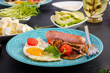 English breakfast - fried egg, tomatoes, sausage and bacon.