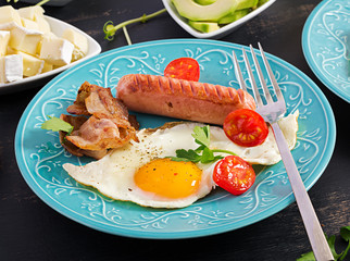 English breakfast - fried egg, tomatoes, sausage and bacon.