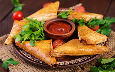 Asian food. Samsa (samosas) with chicken fillet and cheese on wooden background.