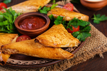 Asian food. Samsa (samosas) with chicken fillet and cheese on wooden background.