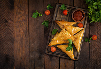 Asian food. Samsa (samosas) with chicken fillet and cheese on wooden background. Top view