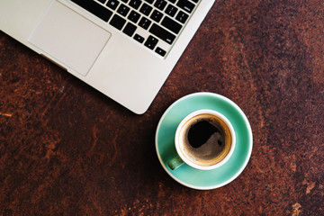 Top view of laptop with cup of coffee and notebook on vintage table with rust