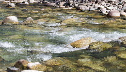 Water in the mountain raging river. Beautiful natural background of stones and water. Texture of clear water and fast river. Backdrop with copy space