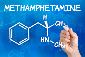 Hand with pen drawing the chemical formula of methamphetamine