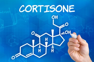 Hand with pen drawing the chemical formula of cortisone