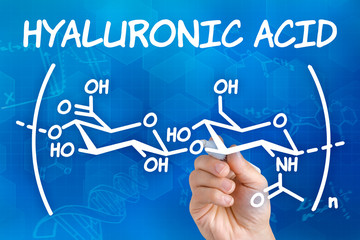 Hand with pen drawing the chemical formula of hyaluronic acid