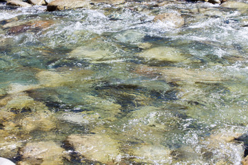 Water in the mountain raging river. Beautiful natural background of stones and water. Texture of clear water and fast river. Backdrop with copy space