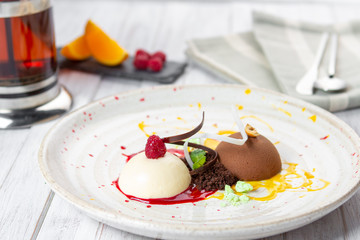 Italian Colorful ice cream scoops semifreddo with chocolate and raspberry on white plate on wooden background