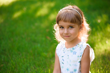 Portrait of a beautiful young little girl in summer park