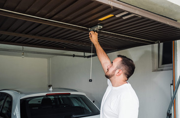 iron garage door. man opens garage door made of sheet metal