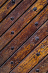 Close up of old vintage wooden door with metal furniture.  Brown wooden fence background texture.