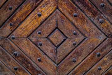 Close up of old vintage wooden door with metal furniture.  Brown wooden fence background texture.