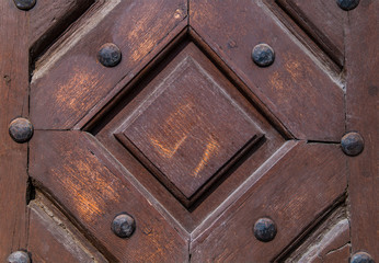 Close up of old vintage wooden door with metal furniture.  Brown wooden fence background texture.