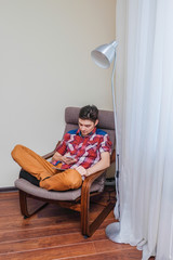 A man uses a digital tablet sitting in a chair.