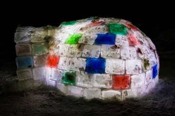 Random color igloo, illuminated from the inside on a dark background.