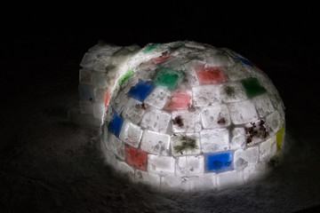 Random color igloo, illuminated from the inside on a dark background.