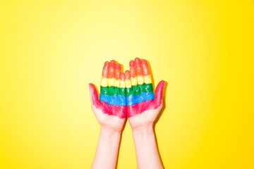 LGBT flag painted on hands on yellow background