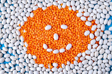 Red lentils in the shape of a circle with a smile on the white fosoli.