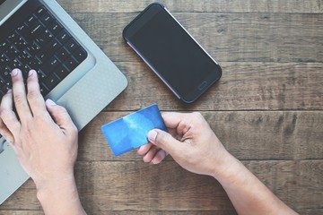 Blank screen smartphone for application mock up with man using credit card and laptop computer