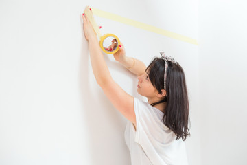 Woman masking off part of the wall before paint job. Diy home renovation.
